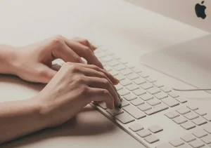 Manos tecleando delante de un teclado.