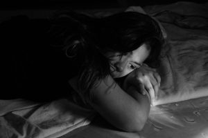 Chica triste en una cama en una imagen en blanco y negro